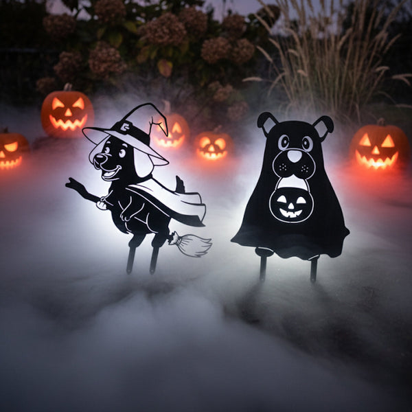 The Witch Dog and Ghost Dog matte black steel silhouettes in fog among glowing jack-o'-lanterns
